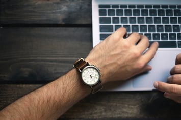Man looking at watch over laptop