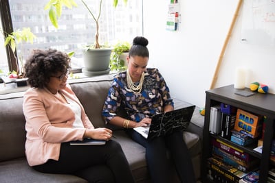 Two women working together on office couch