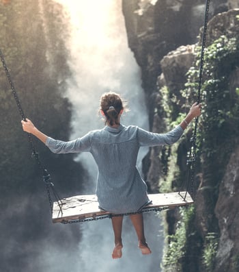 Figure swinging over waterfall