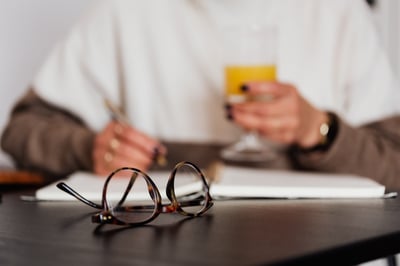 Eye glasses in front of person working through notebook