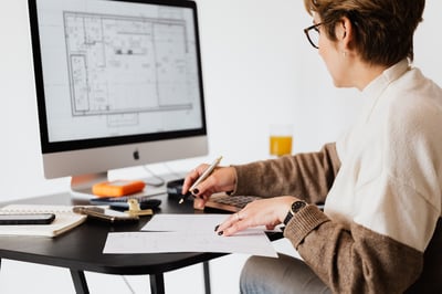 Woman working in front of house plans on computer